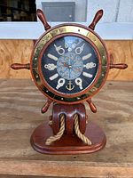 Front view showing the entire nautical clock mounted on wooden base with rope detail.