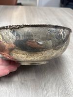 Side view of tarnished silver bowl showing decorative rim detail and tarnished surface.
