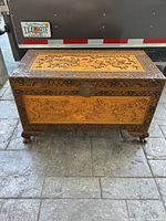 Front view of the vintage carved oriental chest showing the intricate floral and bird carvings and central metal latch