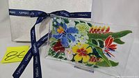 Front view of rectangular fused glass tray with colorful floral design, original box, and Dillard's ribbon.
