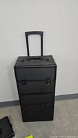 Front view of black rolling makeup case with extended telescopic handle