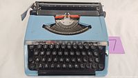 Front view of Brother Charger 11 manual typewriter in blue with visible black and red ink ribbon and black keys.
