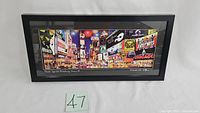 Framed 3D art print showing a panoramic view of Times Square with Broadway show signage, in a black frame against a white background.