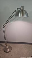 Photo of the full large adjustable metal floor lamp showing its base, adjustable arm sections, and dome-shaped shade.
