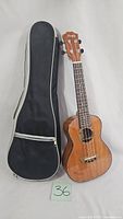 Front view of the Muigi ukulele and the black padded gig bag with zipper pocket.