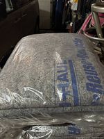 Stack of gray heavy duty U-Haul moving blankets wrapped in plastic showing blue U-Haul logo.