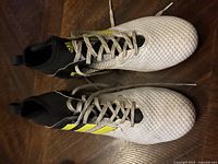 Pair of Adidas men's size 10 cleats, white with black and yellow stripes, mid-top style