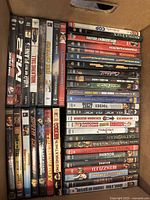 Box containing various popular DVDs arranged in rows with visible titles such as Mission: Impossible II, Walking Tall, and Blue Brothers.