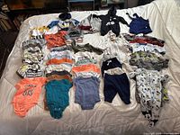 Wide view of all children's clothing laid out on a bed shows variety of colors and styles, demonstrating quantity and condition