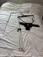 Complete unassembled Jolly Jumper frame, black harness, and supporting legs laid on bed.