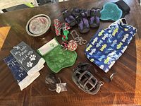 All items arranged on wooden table showing assortment of dog gear including clothing, grooming, feeding, training and play items.