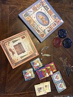 Lot arranged on wooden table showing family record and photo album books, small stained glass bird and musical note ornaments, four small decorative gift boxes and three glass sea motifs.