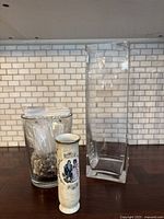 Three vases grouped: two large clear glass vases and one small decorative vase with gold rim.