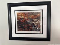 Framed artwork titled The Red Maple by Ay Jackson showing autumn landscape featuring red maple leaves and rocky river.