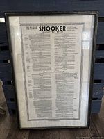 Framed print showing the official rules of snooker printed in black text on a light background, with a decorative border. Frame has black finish with minor wear.