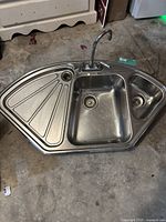Photo showing entire stainless steel sink with two basins, drying rack, and faucet from a slight angle.