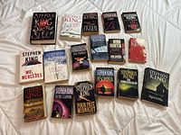 Books laid out on bed, showing entire lot of Stephen King novels including paperbacks and one hardcover copy of Doctor Sleep