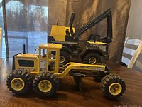 Side view of both Tonka toy trucks, excavator behind and motor grader in front