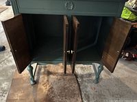 Front view of the wood cabinet with both doors open, showing dark stained wood interior and brass knobs on doors.