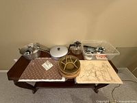 Overview of all kitchen items on table including cookware, serving dish, linen, and artwork