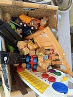 Photo showing a basket containing a wooden toy crane, wooden alphabet blocks, a Tonka toy truck, and toy keyboard