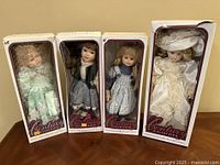 Four boxed Century Collection porcelain dolls on a wooden surface, all in original packaging, showing doll details and labeling.