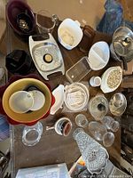 Various kitchen bowls, plates, glassware, and containers displayed on a table showing color variety and stacking arrangement.