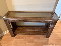 Wooden sofa table showing side angle with glass inset top and lower shelf.