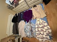 Vintage dress clothes laid out on a bed showing various jackets, sweaters, and blouses in assorted styles and colors.