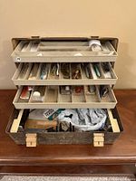 Full view of open vintage tackle box showing multiple trays of fishing lures and accessories