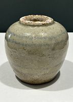 Front view of antique round stoneware ginger jar showing glazed surface with blue horizontal bands and rustic wear