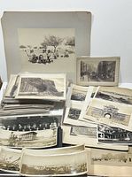 Photo showing multiple albumen photographs including carriages and city scenes stacked and spread on a table, with visible age wear on mounts.