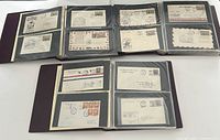 Three Uniself binders opened flat showing multiple black pages with clear sleeves holding Canada first flight covers