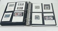 Opened binder showing multiple pages with Canadian postage stamps mounted on black album pages with labels.