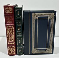 Front standing view of three leather-bound Franklin Library books showing detailed gold tooling on spine and covers: Gargantua and Pantagruel (red spine), The Mill on the Floss (green spine), and a third blue/black book.