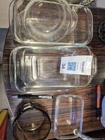Top-down photo showing multiple rectangular glass baking bread pans and a circular serving dish stacked on a wood surface.