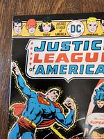 Close-up photo showing the top portion of the Justice League of America comic book cover with Superman prominently displayed and part of the title visible.