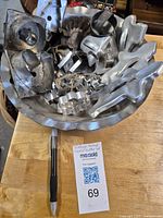 Photo displaying a collection of vintage metal cookie cutters and a metal pie plate arranged inside the pie plate.