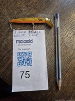 Fishing lure placed next to a pen and auction tag to show size and detail