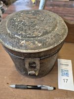 Front angle showing the flip lid and latch with heavy rust on the tin lunch pail.