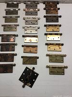 Overview of all 24 hinges in various finishes, purple, black, brass and aged metal shown on white background