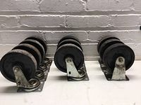 Seven swivel caster wheels visible, showing metal mounting plates with swivel mechanism and black rubber wheels with some rust and dirt.