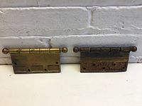 Pair of 5" x 5" brass hinges with ball finials, laid side by side showing front and back surfaces.