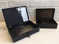 Open view of two black metal boxes, showing interior condition and compartments