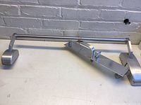 Full view of silver metal Dorex push bar door hardware with mounting brackets and latch mechanism on a white surface.