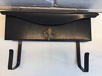 Close-up angled view showing the mailbox with integrated newspaper holder hooks below.