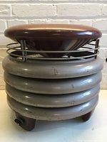 Front view of vintage fan stool base with cushioned top seat showing wear.