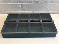 Front view of teal plastic parts bin showing four transparent spring-loaded lids opened horizontally.