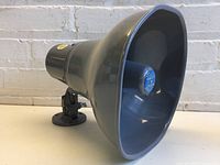 Side angled view of grey horn-shaped speaker with mounting bracket and blue Atlas Soundolier logo on driver in center.
