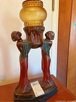 Full view of Art Deco figural lamp with amber glass shade on wooden surface
